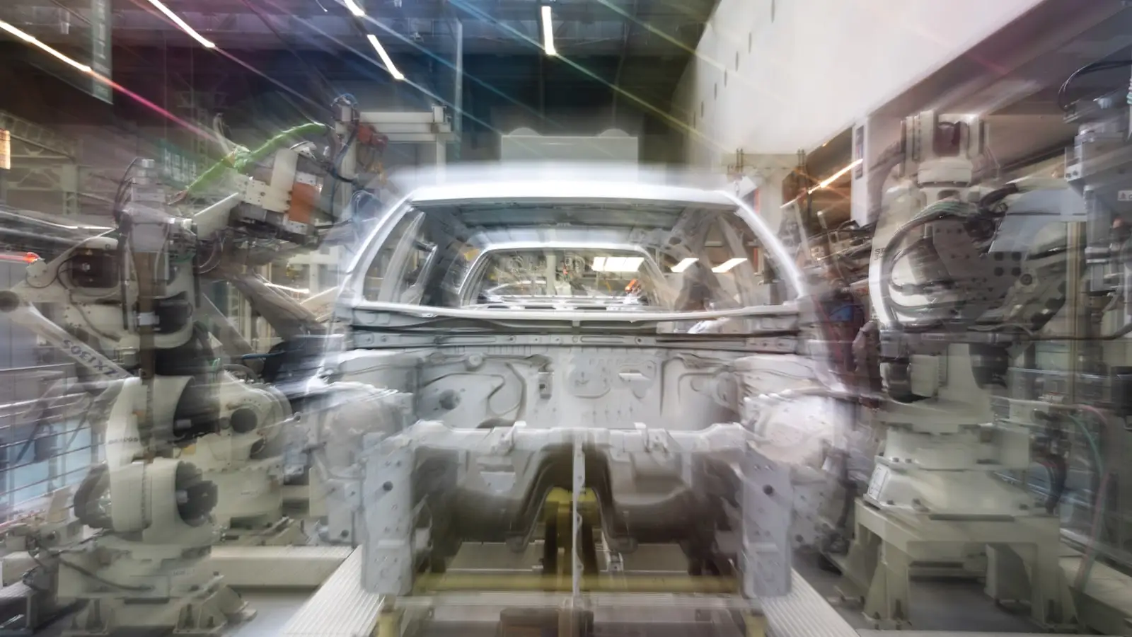 Robot arms working on a car body in an assembly line