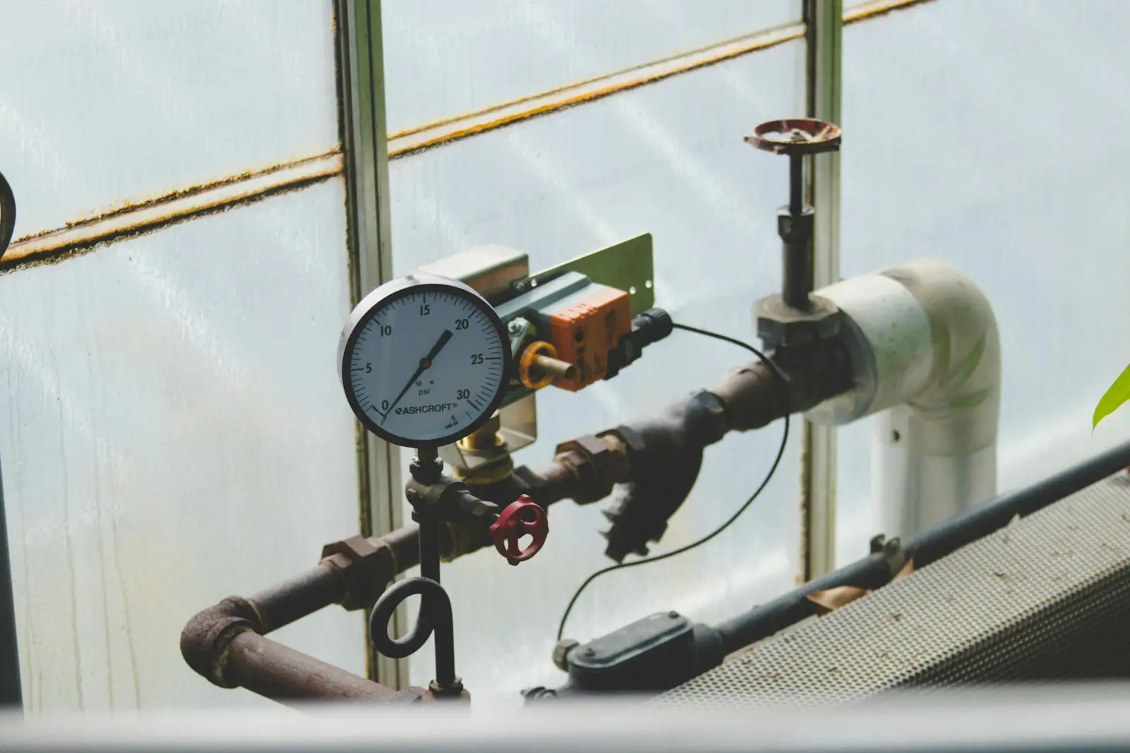 A pressure gauge, valve and sensor mounted on plant pipework
