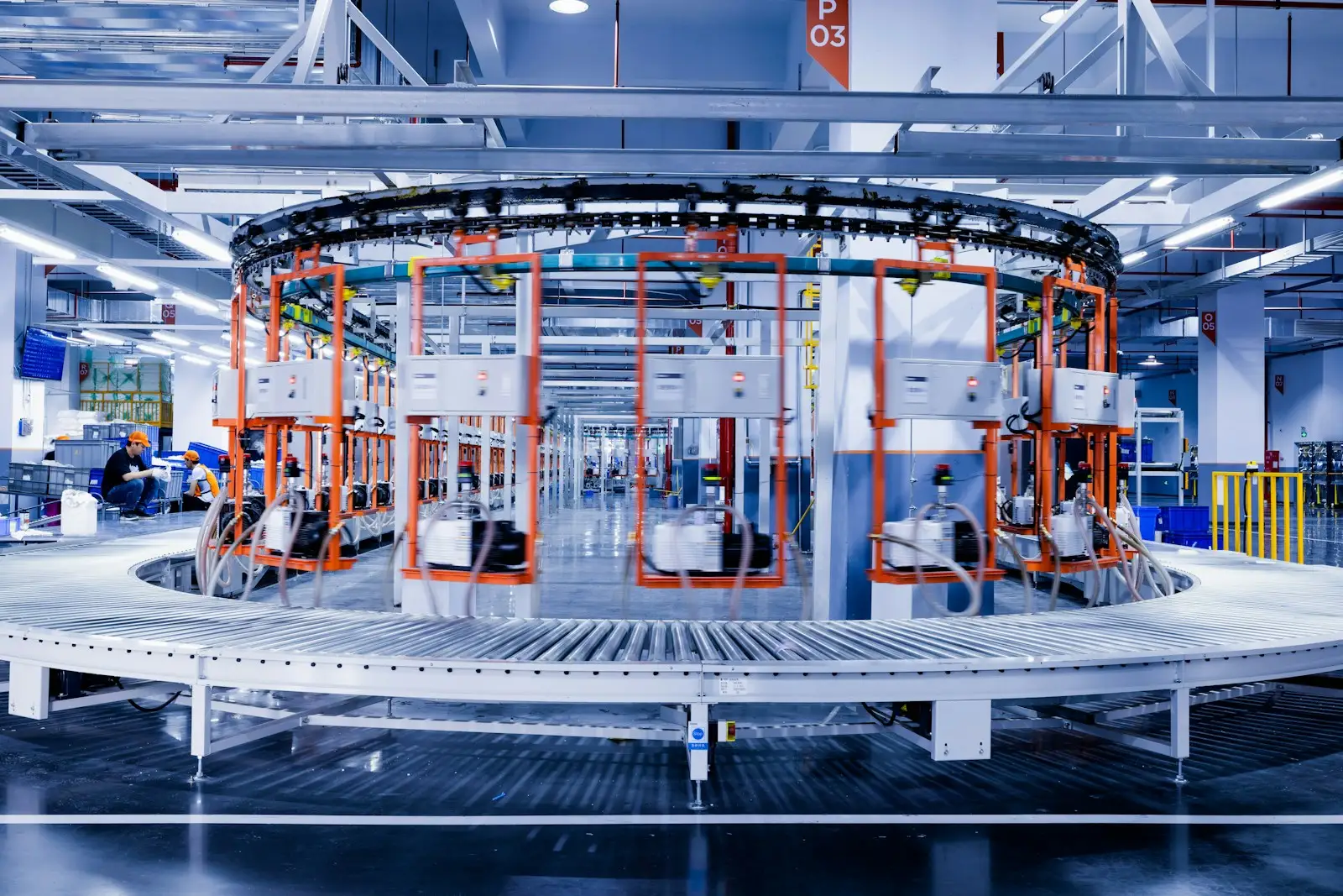 A wide view of a factory hall with a circular assembly carousel and numbered bays