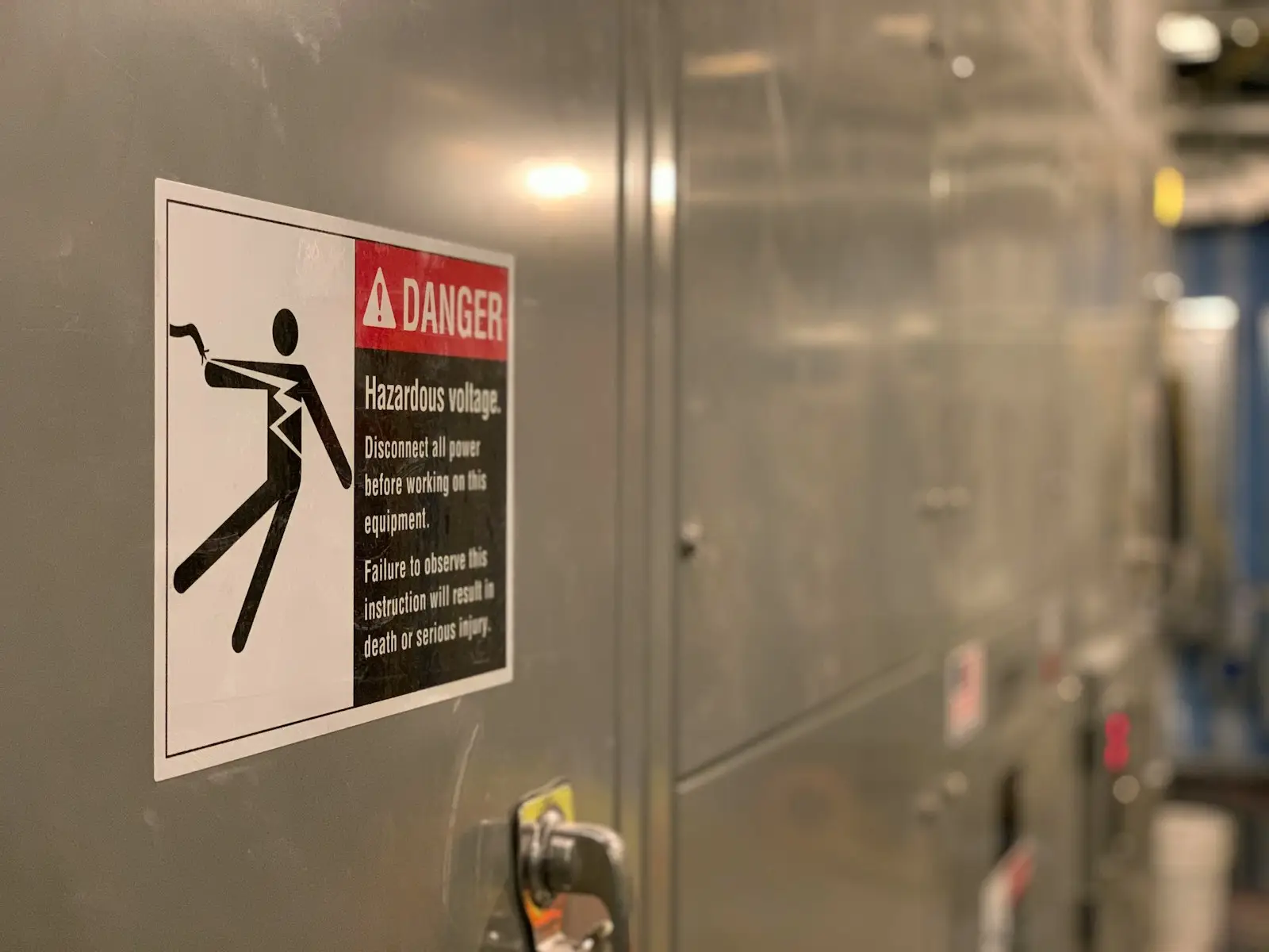 A hazardous voltage warning sign on an electrical switchgear cabinet