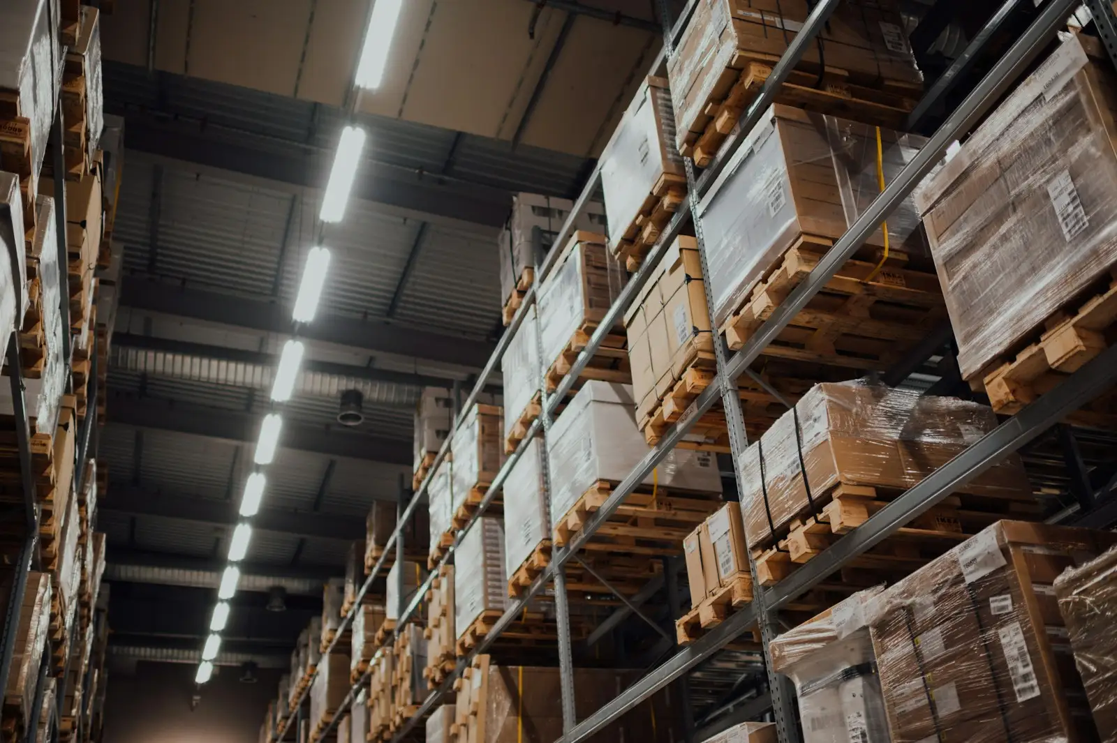 Pallet racking stacked with wrapped cartons down a warehouse aisle