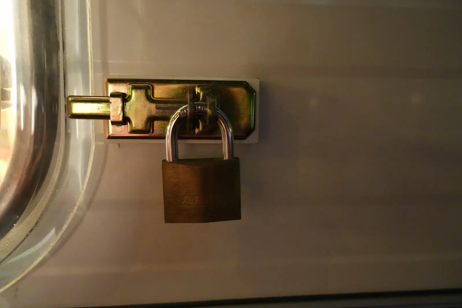 A brass padlock securing the latch on a panel door