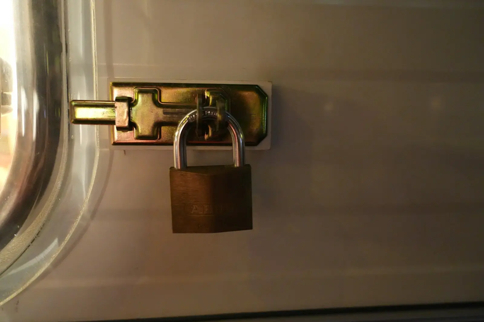 A brass padlock securing the latch on a panel door