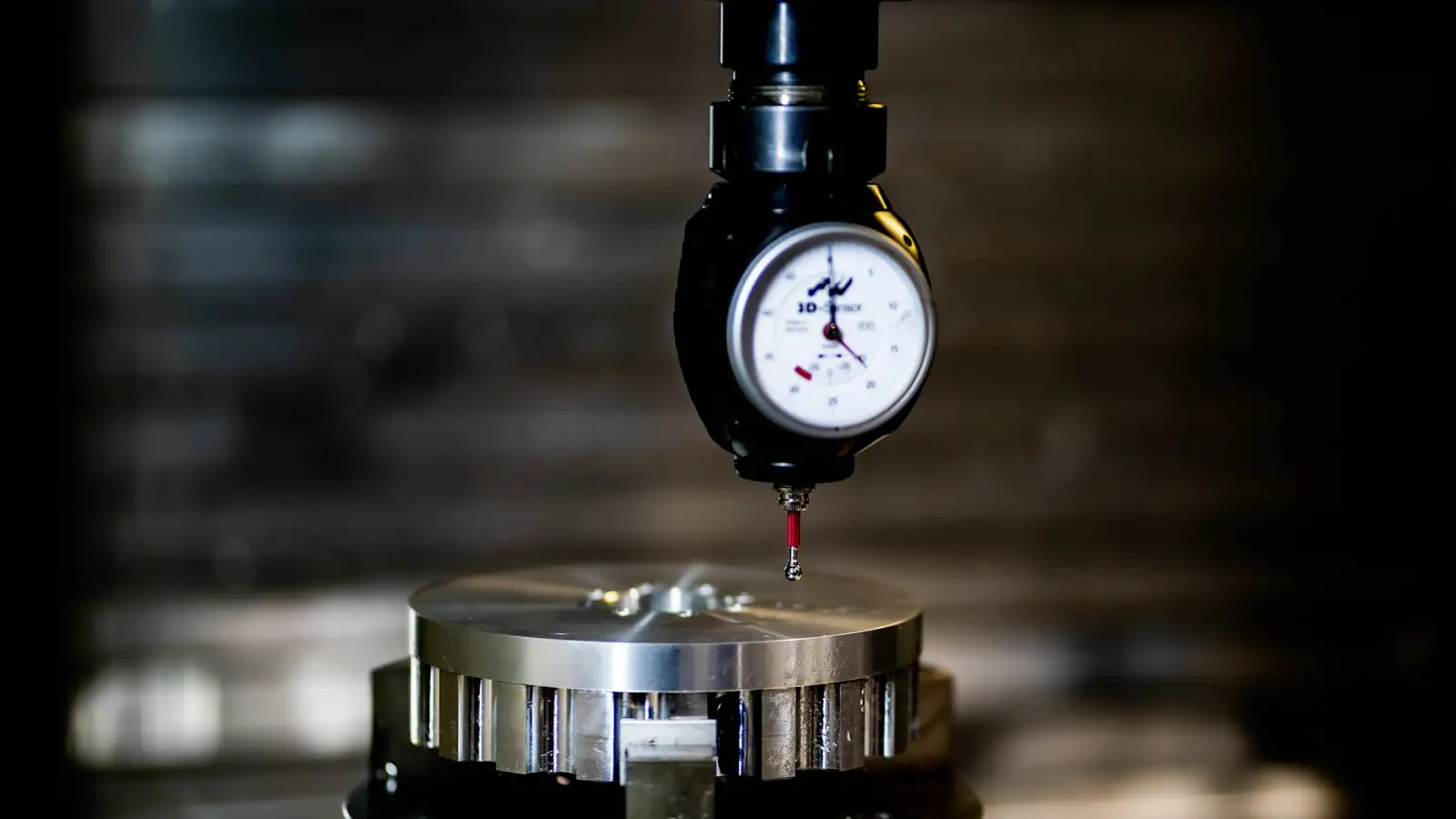 A dial indicator on a fixture measuring a machined metal disc