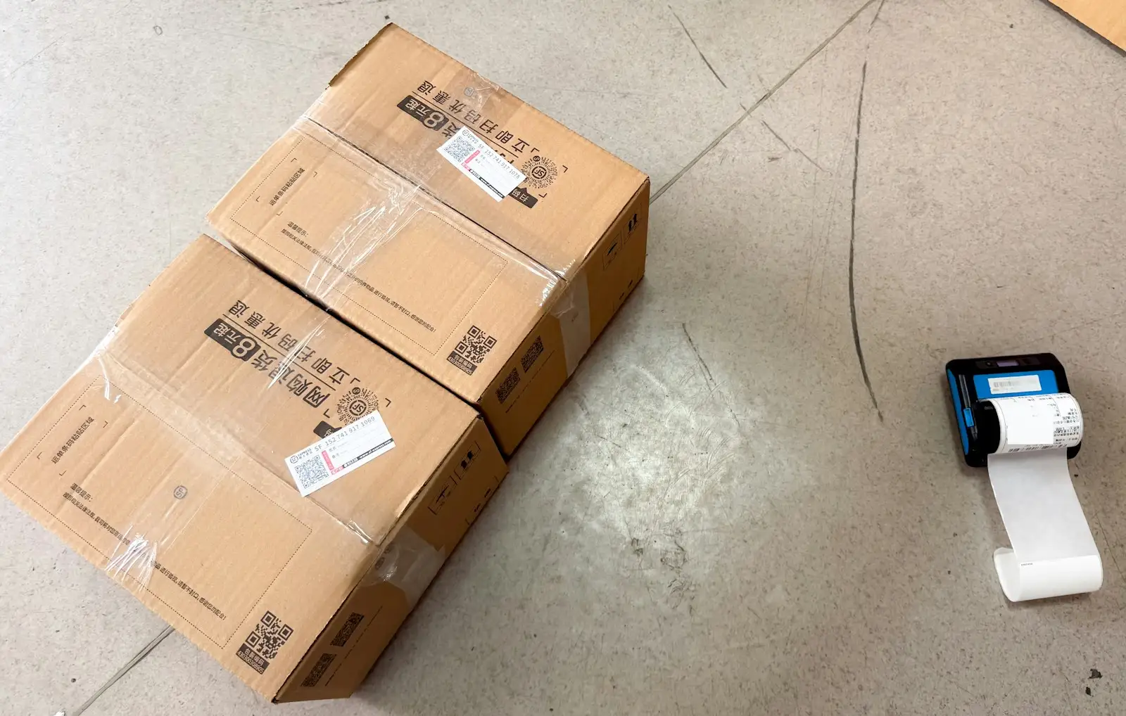 Two labelled cartons with QR codes next to a portable label printer