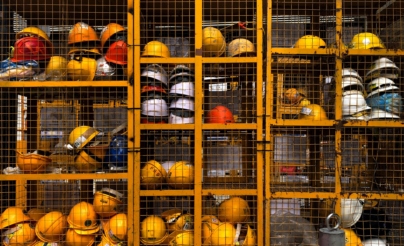 Hard hats stacked in yellow wire lockers at a plant entrance.