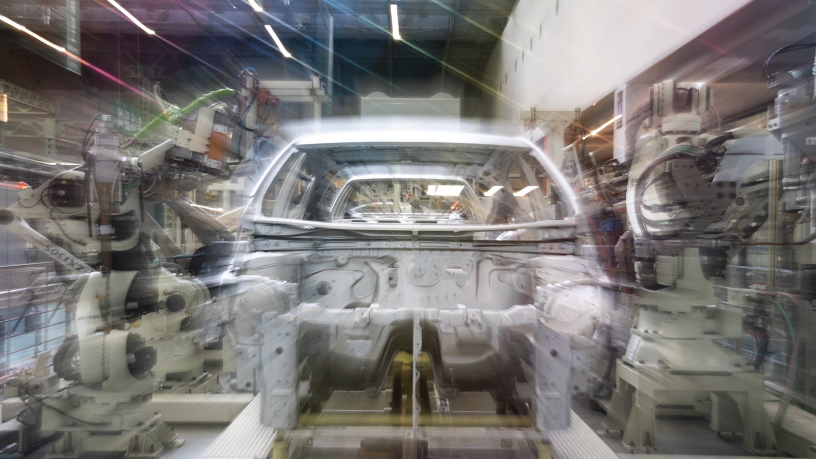 Robot arms working on a car body in an assembly line